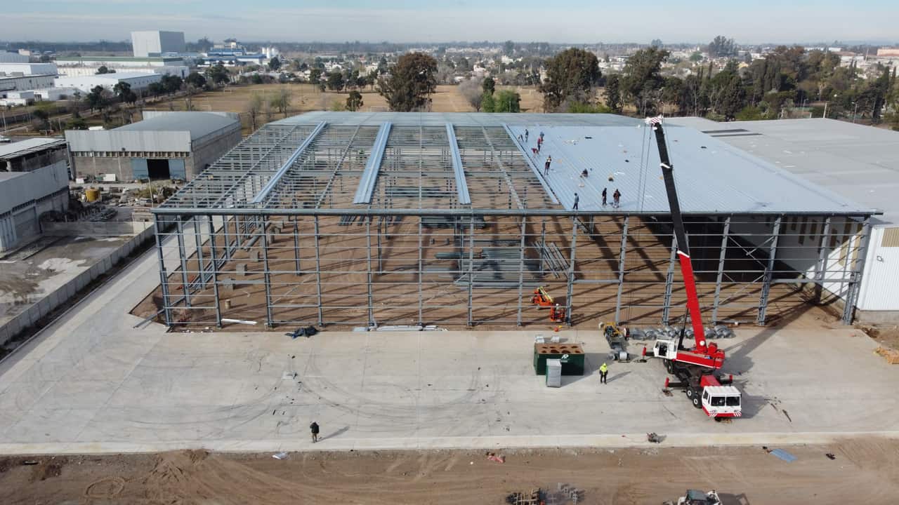 Vista aérea de una nave industrial en montaje, con la estructura metálica levantada y la cubierta en colocación